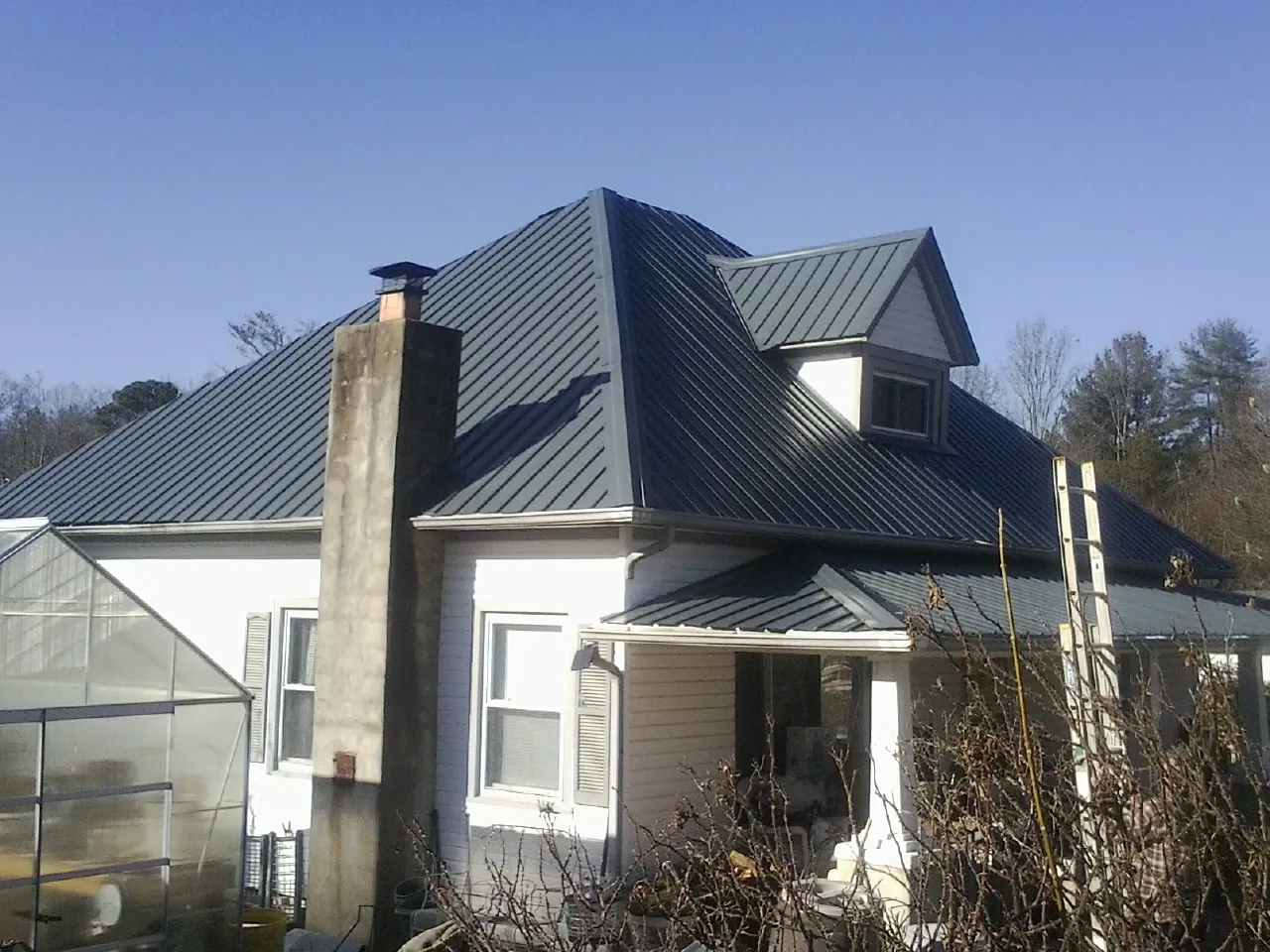 Dark blue standing seam metal roof on a white farmhouse with dormer — Slate & Tile Roof Repair by Roofing Brothers in Reedley