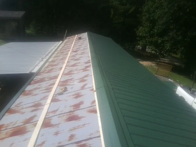 Old rusted panels beside newly installed green metal roofing — Wind Damage Roof Repair by Roofing Brothers in Reedley