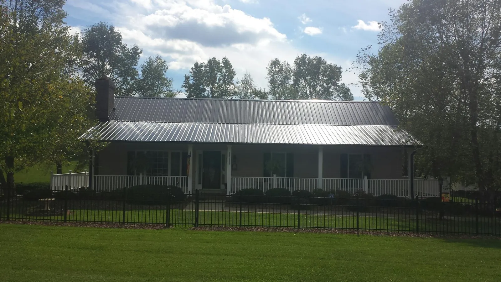 Gray metal roof on a brick ranch with a full width front porch — Gutter Guard Installation work by our crew in Reedley
