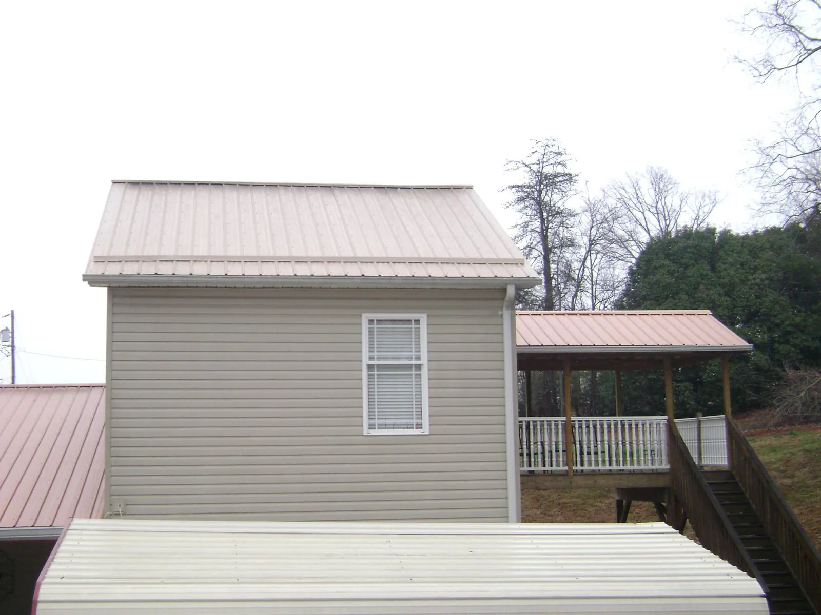 Tan metal roofs on a two story addition and attached porch, from a Roof Replacement job in Reedley